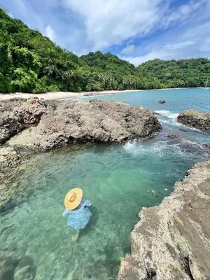 a person in a straw hat in the water on a beach at Villas Roma Del Mar in Playa Naranjo