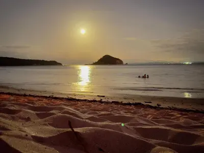 a group of people swimming in the ocean at sunset at Villas Roma Del Mar in Playa Naranjo
