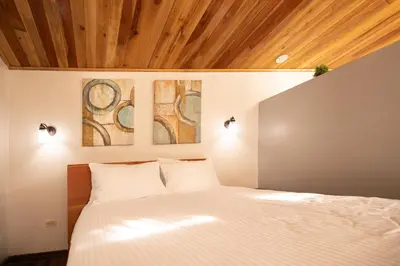 a bedroom with a bed with two paintings on the wall at Gamaí Monteverde Tiny House in Monteverde Costa Rica