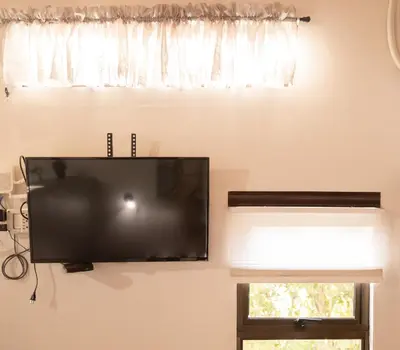 a flat screen tv hanging on a wall next to a window at Gamaí Monteverde Tiny House in Monteverde Costa Rica