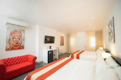 a hotel room with two beds and a red couch at Shana by the Beach Manuel Antonio in Manuel Antonio