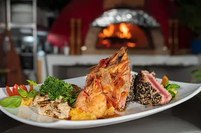 a plate of food with shrimp on a table with a fireplace at Shana by the Beach Manuel Antonio in Manuel Antonio