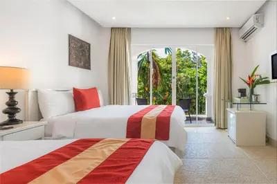 a hotel room with two beds and a window at Shana by the Beach Manuel Antonio in Manuel Antonio