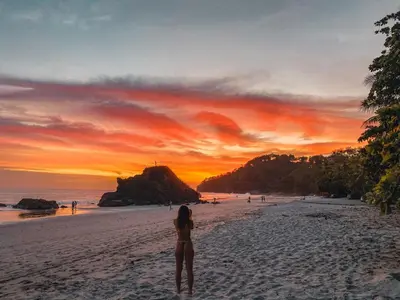 a woman standing on a beach at sunset at Shana by the Beach Manuel Antonio in Manuel Antonio