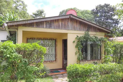 a small yellow house with a gate and trees at Casa Copalchi in Monteverde Costa Rica