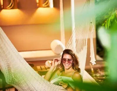 a woman in sunglasses sitting in a hammock at Cala Luna Boutique Hotel & Villas in Tamarindo