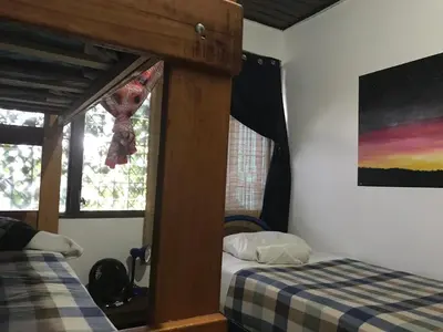 a bedroom with two beds and a painting on the wall at In the Wind Hostel and Guesthouse in San José
