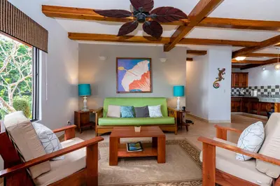 a living room with a green couch and a ceiling fan at Villas Alturas in Dominical