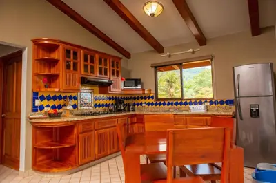 a kitchen with wooden cabinets and a table and a refrigerator at Villas Alturas in Dominical