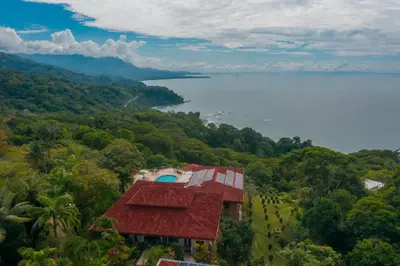a house on a hill with a view of the water at Villas Alturas in Dominical