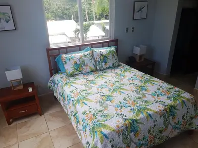 a bedroom with a bed with a floral comforter and a window at Casa Malia Guapinol #8 in Tamarindo