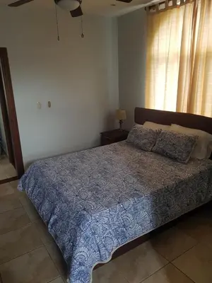 a bedroom with a bed with a blue comforter and a window at Casa Malia Guapinol #8 in Tamarindo