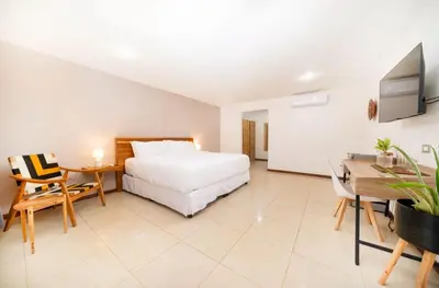 a bedroom with a bed and a table and a desk at Hotel Arco Iris in Tamarindo