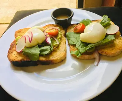 a white plate with two sandwiches with lettuce and tomatoes at Hotel Arco Iris in Tamarindo