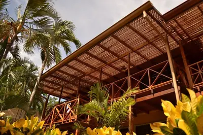a building with a wooden roof with palm trees at Hotel Arco Iris in Tamarindo