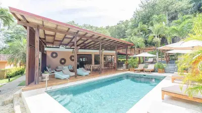 a swimming pool with a pavilion next to a house at Hotel Arco Iris in Tamarindo