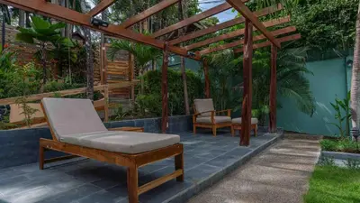 a patio with a wooden pergola and a chair and a table at Hotel Arco Iris in Tamarindo
