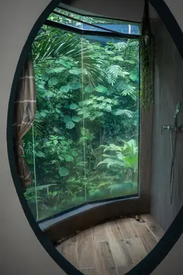 a round window with a view of a forest at Canaima Chill House in Santa Teresa Beach
