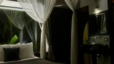 a bedroom with a bed with white curtains and a window at Canaima Chill House in Santa Teresa Beach