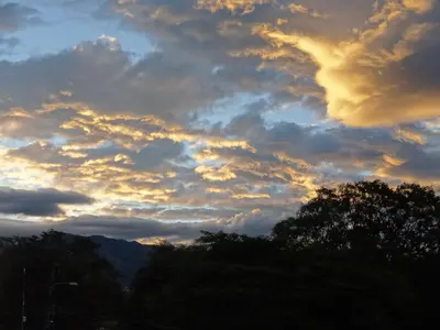 a cloudy sky at sunset with trees in the foreground at Casa Nadette in Guácima