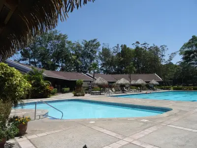 a swimming pool with umbrellas and a resort at Casa Nadette in Guácima