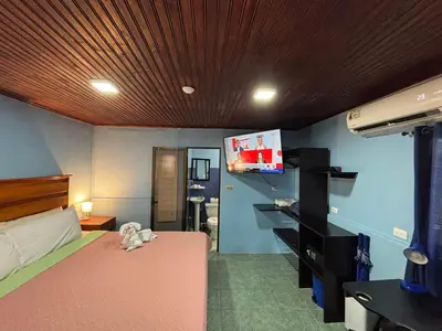 a bedroom with a bed and a flat screen tv at Pura Vida Aparment - Downtown La Fortuna in Fortuna