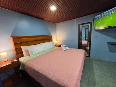 a bedroom with a bed with a tv on the wall at Pura Vida Aparment - Downtown La Fortuna in Fortuna