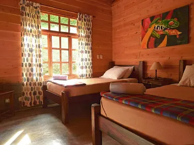 a bedroom with two beds in a log cabin at Rancho Amalia in Naranjo