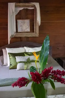 a bedroom with a bed with a vase of flowers at The House of Hummingbird, Costa Rica in Atenas