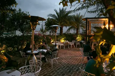a group of people sitting at tables in a patio at Hotel Presidente in San José