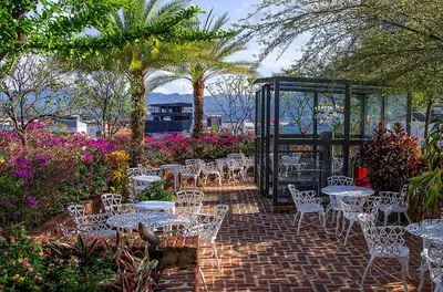 a patio with white tables and chairs and flowers at Hotel Presidente in San José