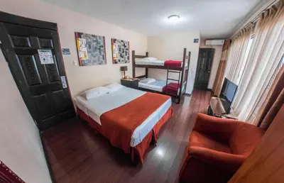 a hotel room with a bed and a couch and a chair at Hotel Casa Colon in San José