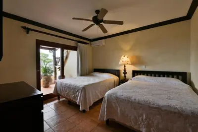 a bedroom with two beds and a ceiling fan at Club del Mar Oceanfront in Jacó