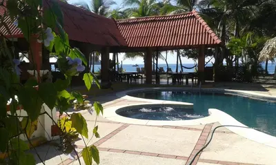 a swimming pool with a gazebo next to the ocean at Hotel Las Brisas del Pacifico in Sámara
