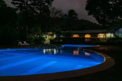 a swimming pool at night with a house in the background at Malekus Mountain Lodge in Aguas Claras