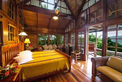 a bedroom with a yellow bed in a room with windows at Aguila de Osa Rainforest Lodge in Drake