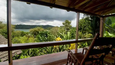 a porch with a view of the water and trees at Aguila de Osa Rainforest Lodge in Drake