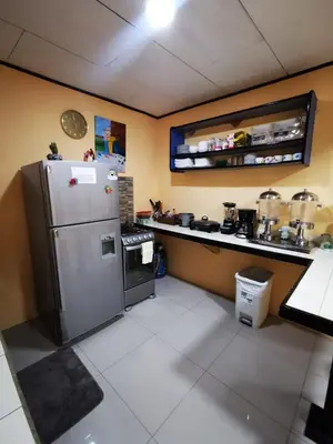 a kitchen with a refrigerator and a counter with pots and pans at Toucan Hostel in Alajuela City
