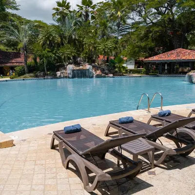 a swimming pool with two wooden tables and chairs at CC Beach Front Papagayo All Inclusive in Papagayo, Guanacaste