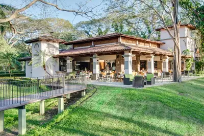 a building with tables and chairs in a park at CC Beach Front Papagayo All Inclusive in Papagayo, Guanacaste