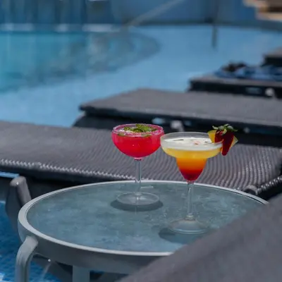 two cocktails sitting on a table next to a pool at CC Beach Front Papagayo All Inclusive in Papagayo, Guanacaste