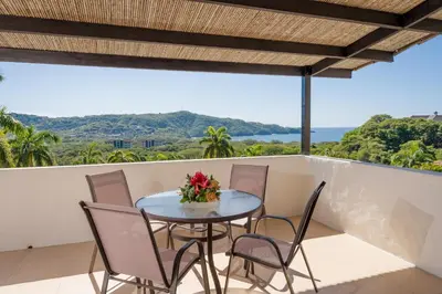 a table and chairs on a balcony with a view of the ocean at Villas Sol Beach Resort in Playa Hermosa