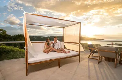 a man and a woman sitting on a bed on a balcony at Villas Sol Beach Resort in Playa Hermosa