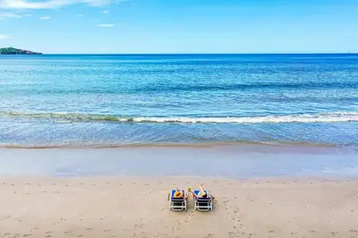 two people sitting in beach chairs on the beach at Margaritaville Beach Resort Playa Flamingo in Playa Flamingo
