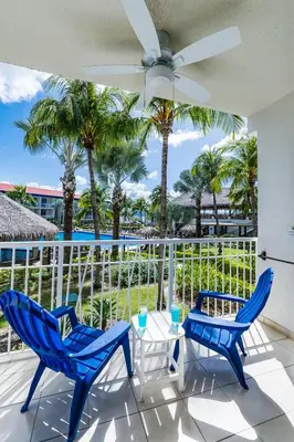 a patio with two chairs and a table and palm trees at Margaritaville Beach Resort Playa Flamingo in Playa Flamingo