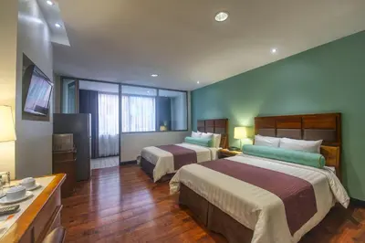 a hotel room with two beds and a television at Balmoral Hotel San José CR, Historic District in San José