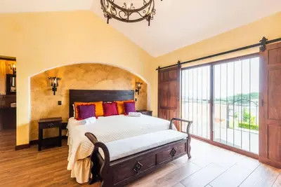 a bedroom with a large bed and a large window at Villa El Retiro Luxury Property in Alajuela City