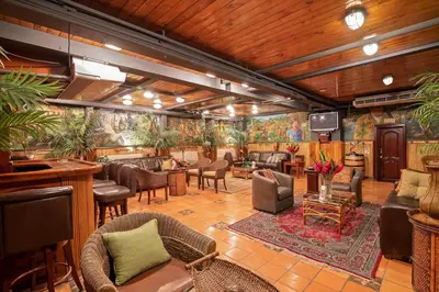 a lobby with a bar with chairs and tables at Hotel Casa Roland San Jose in San José