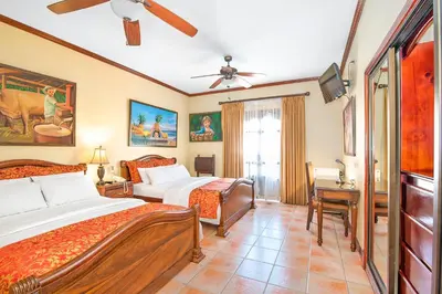 a bedroom with two beds and a desk at Hotel Casa Roland San Jose in San José