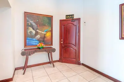 a hallway with a door and a painting and a bench at Hotel Casa Roland San Jose in San José